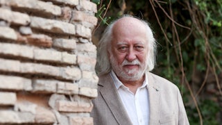 writer Laszlo Krasznahorkai stands behind a brick wall