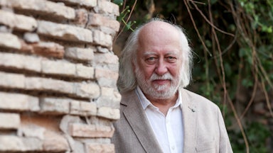 writer Laszlo Krasznahorkai stands behind a brick wall