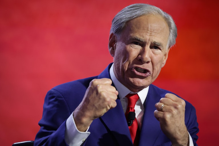 Greg Abbott holds up both his fists while speaking onstage at the Republican National Convention