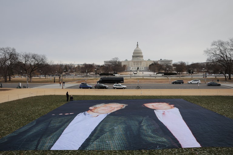 A large banner printed with a photo of Jeffrey Epstein and Donald Trump is laid out on the National Mall in front of the Capitol
