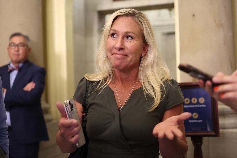 Marjorie Taylor Greene holds out her arms while talking to the press in the Capitol