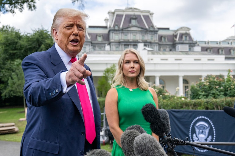 Donald Trump and Karoline Leavitt stand together outside at a press conference.