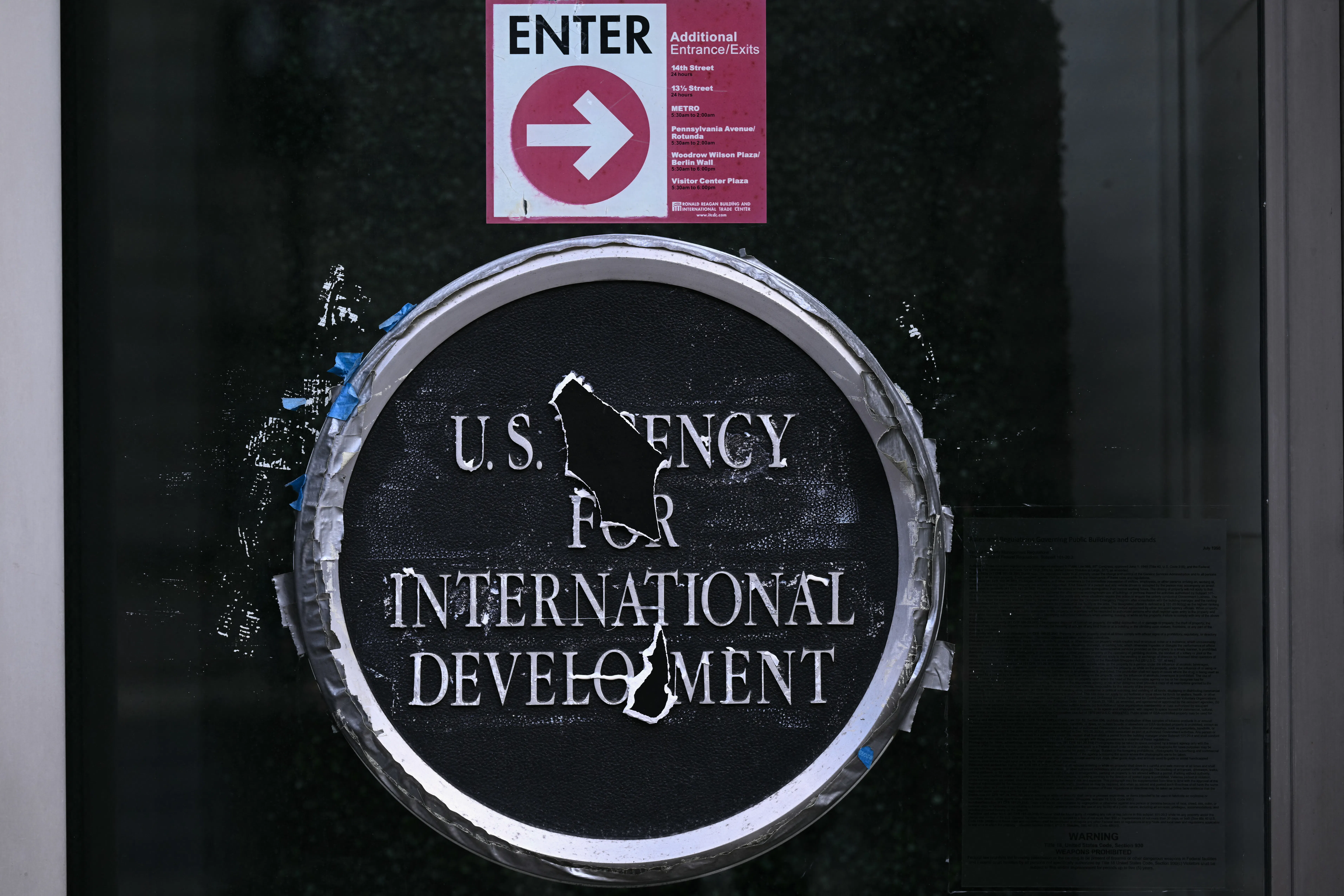 U.S. Agency for International Develoment logo on a glass door. Holes blocks out parts of the words "Agency" and "Development."