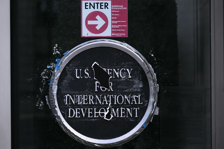 U.S. Agency for International Develoment logo on a glass door. Holes blocks out parts of the words "Agency" and "Development."