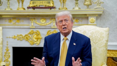 Donald Trump gestures and speaks while sitting in the Oval Office