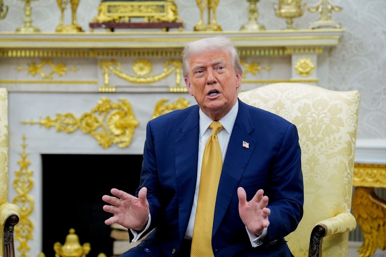 Donald Trump gestures and speaks while sitting in the Oval Office
