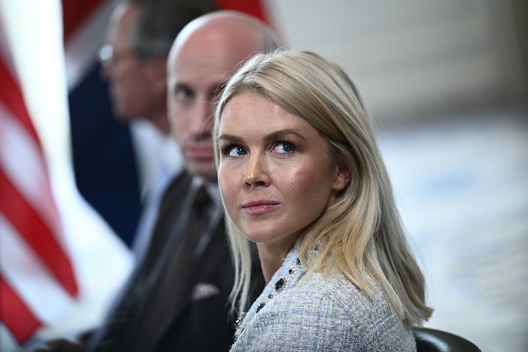 White House press secretary Karoline Leavitt looks over her shoulder while sitting in a press conference