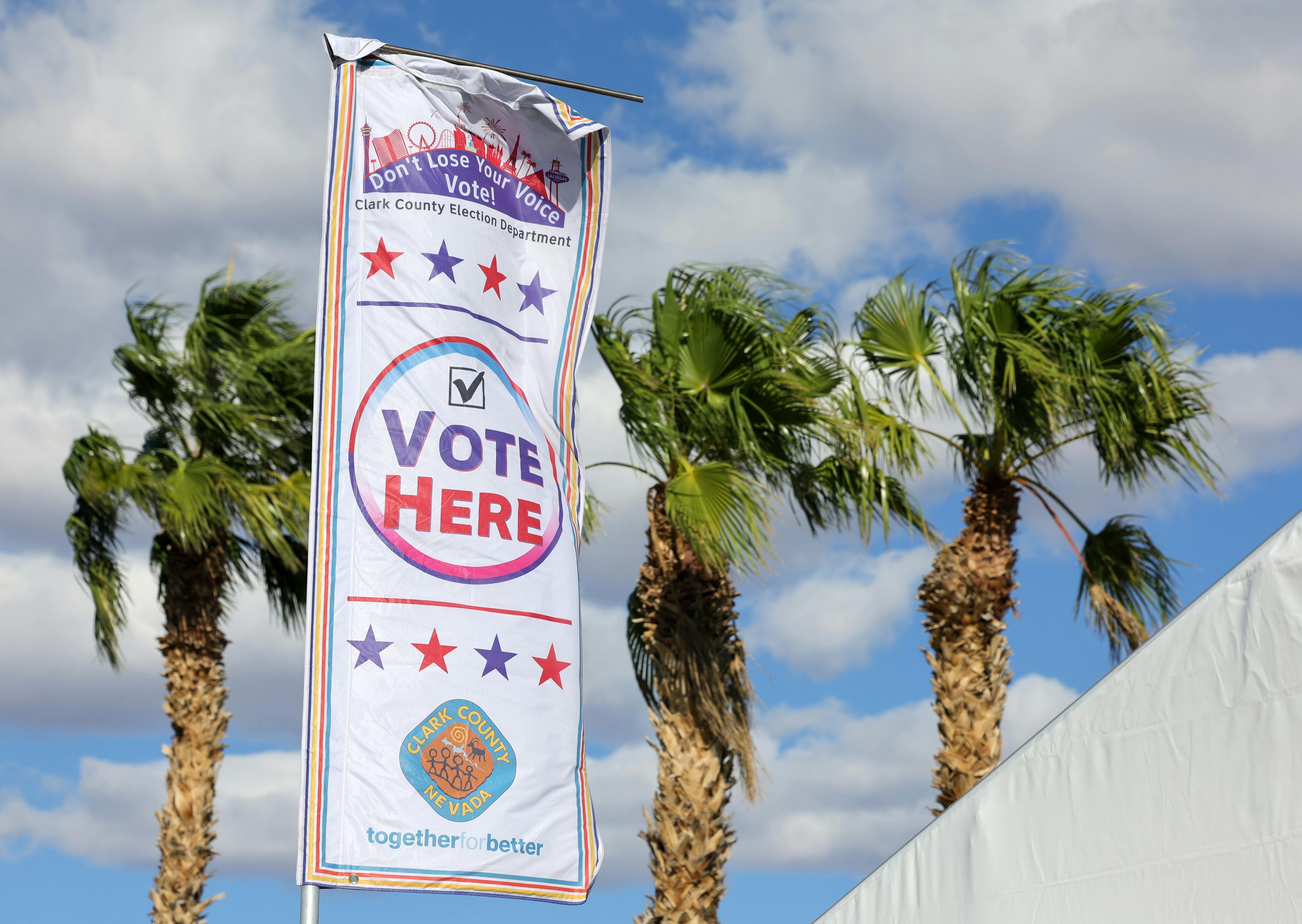 High winds whip a banner marking a voting site on the first day of in-person early voting at a tent at the Thunderbird Family Sports Complex on October 19, 2024 in Las Vegas, Nevada.
