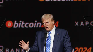 Donald Trump speaks in front of a bitcoin2024 backdrop.