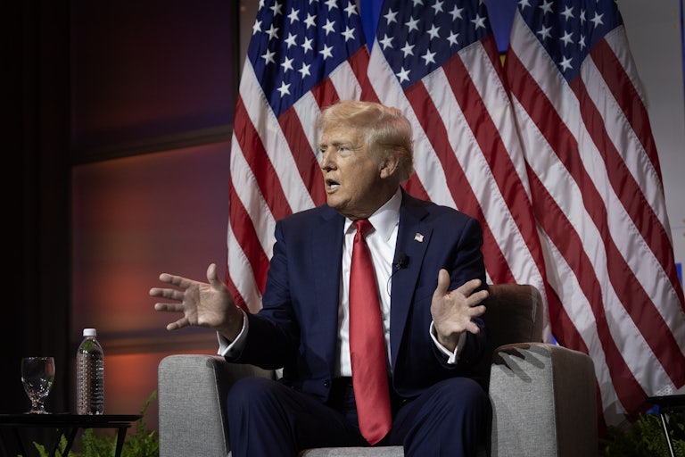 Donald Trump gestures as he sits on stage at a National Association of Black Journalists (NABJ) event