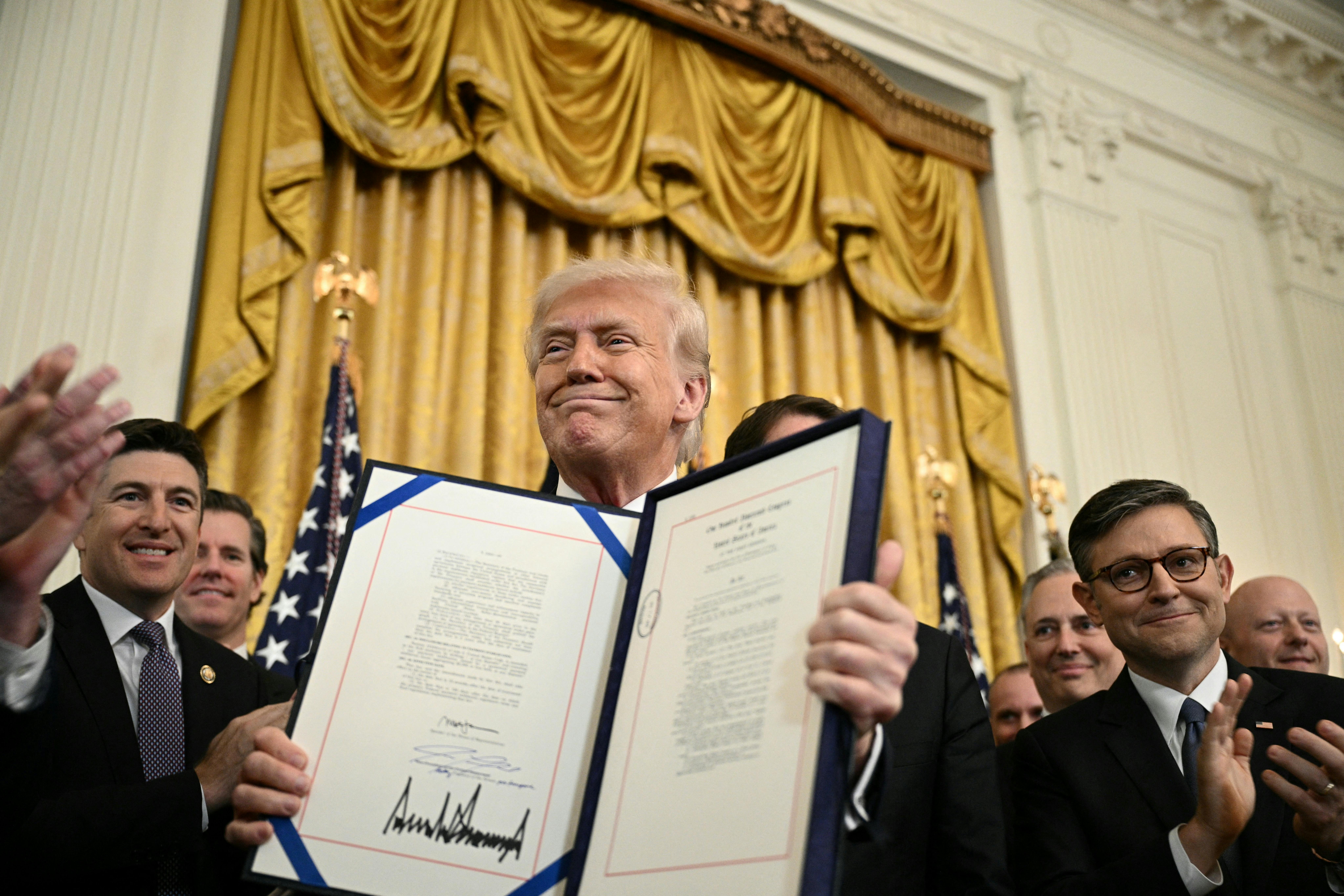 Donald Trump displays the GENIUS Act, which codifies the use of stablecoins -- cryptocurrencies pegged to stable assets like the US dollar or US bonds -- after signing it in the East Room of the White House.