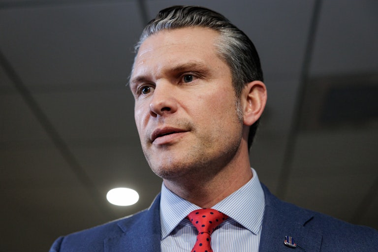 Pete Hegseth looks down while speaking to reporters