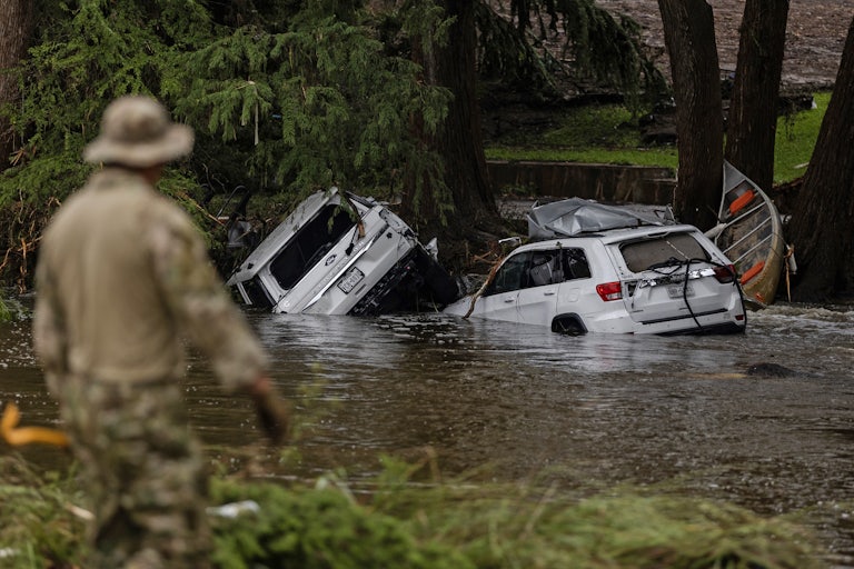 ehicles sit submerged as a search and rescue worker looks through debris for any survivors or remains of people swept up in the flash flooding in Texas.