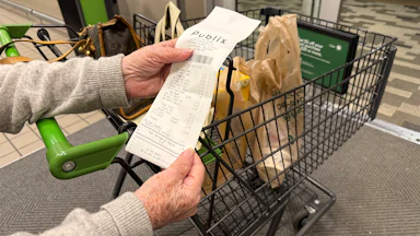 Mature woman reviewing receipt after shopping at Publix supermarket, Florida.