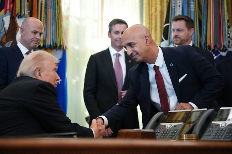 Novo Nordisk CEO Mike Doustdar bends down to shake hands with Donald Trump, who is seated behind his desk in the White House Oval Office.
