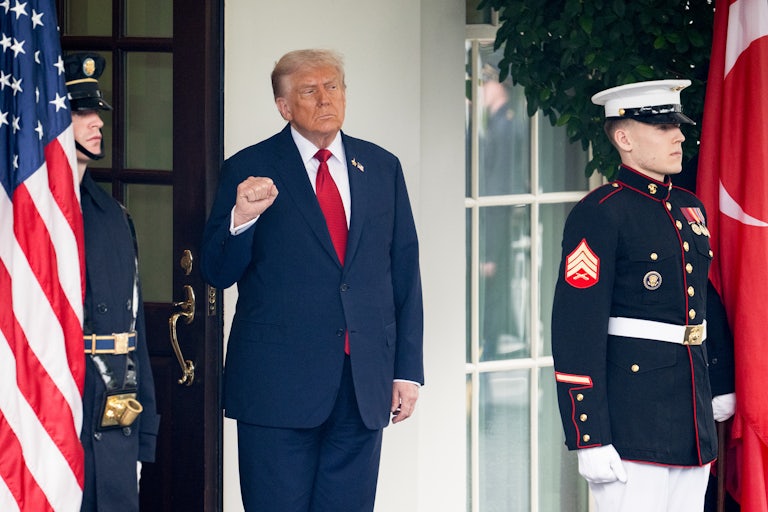 Donald Trump raises his fist while standing outside the White House