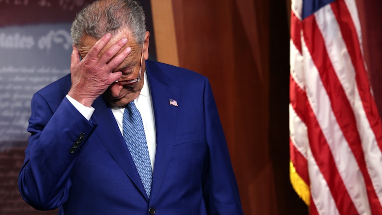 Senate Majority Leader Charles Schumer scratches his head as he attends a press conference.