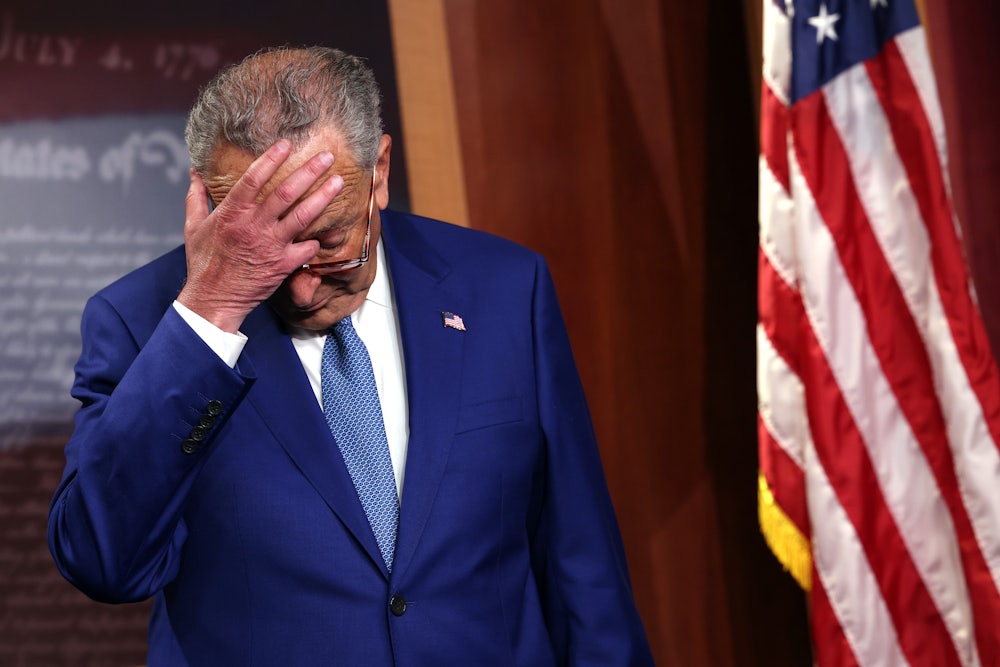 Senate Majority Leader Charles Schumer scratches his head as he attends a press conference.