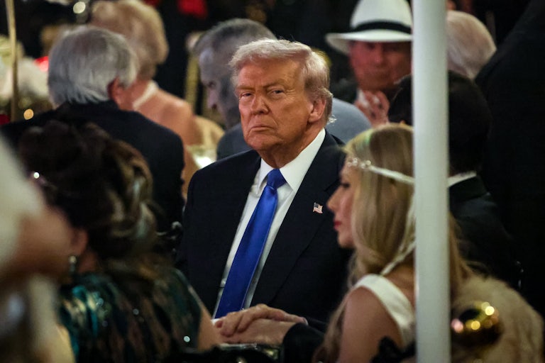 Donald Trump sits in a crowd looking grumpy.