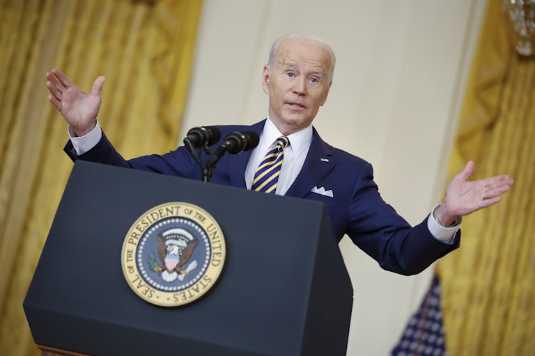 President Joe Biden stands behind a lectern, shrugging.