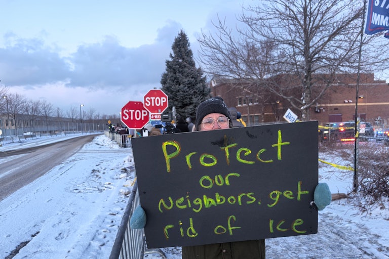 A person holds a sign that says, "Protect our neighbors, get rid of ICE"