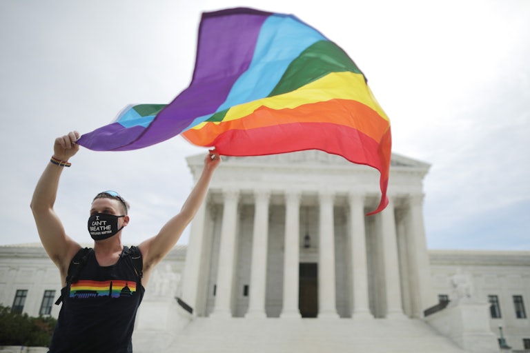 A man waves a rainbow flag outside the Supreme Court.