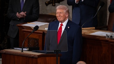 Donald Trump stands and smiles at the lectern during the State of the Union