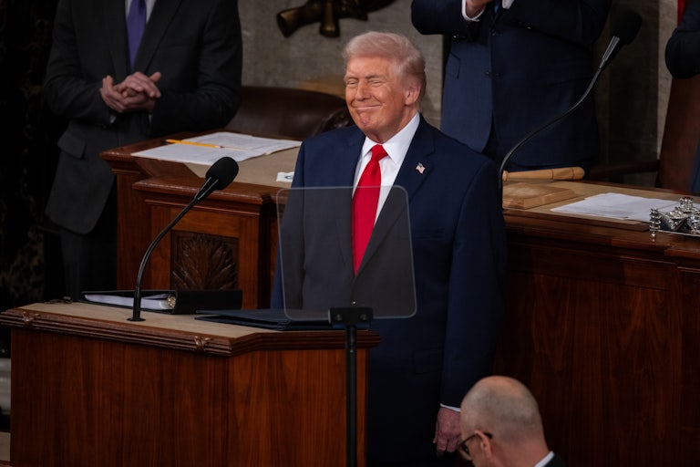 Donald Trump stands and smiles at the lectern during the State of the Union