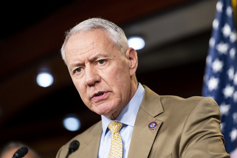 Representative Ken Buck speaks with a mic in front of him