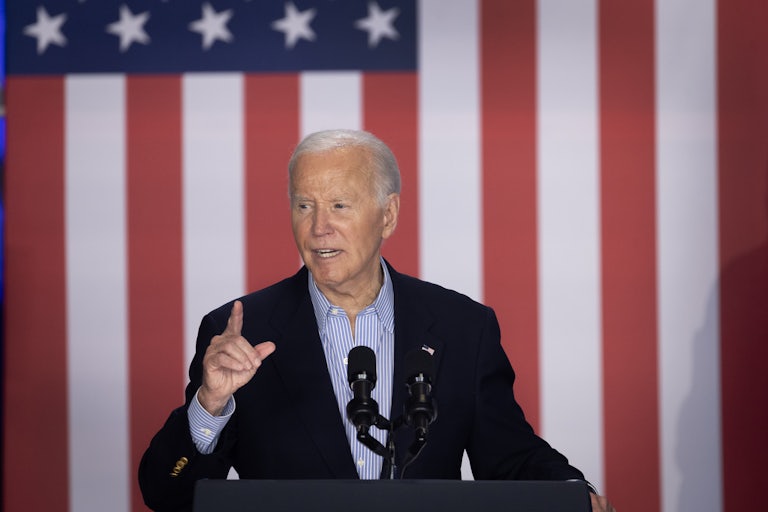 Joe Biden speaks at a lectern. A giant U.S. flag is behind him.
