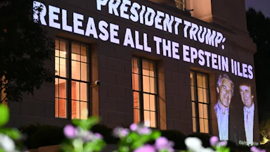 A photo of Donald Trump and Jeffrey Epstein, and the phrase "President Trump: Release all the Epstein Files," are projected onto the U.S. Chamber of Commerce