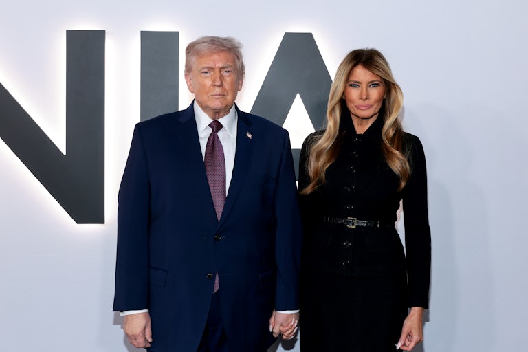 Donald Trump and Melania Trump pose for the cameras in front of a Melania backdrop during the premiere of her documentary at the Kennedy Center. Melania Trump purses her lips like crazy.