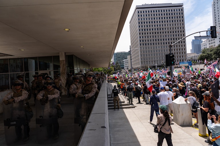 Protesters march past troops stationed in Los Angeles