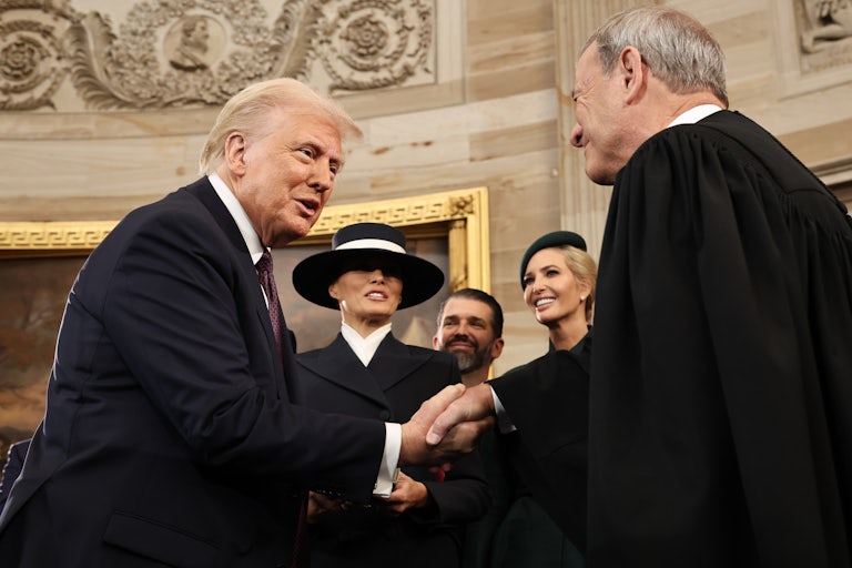 Donald Trump shakes hands with Chief Justice John Roberts during his inauguration as Melania Trump, Ivanka Trump, and Donald Trump, Jr. all look on and smile.