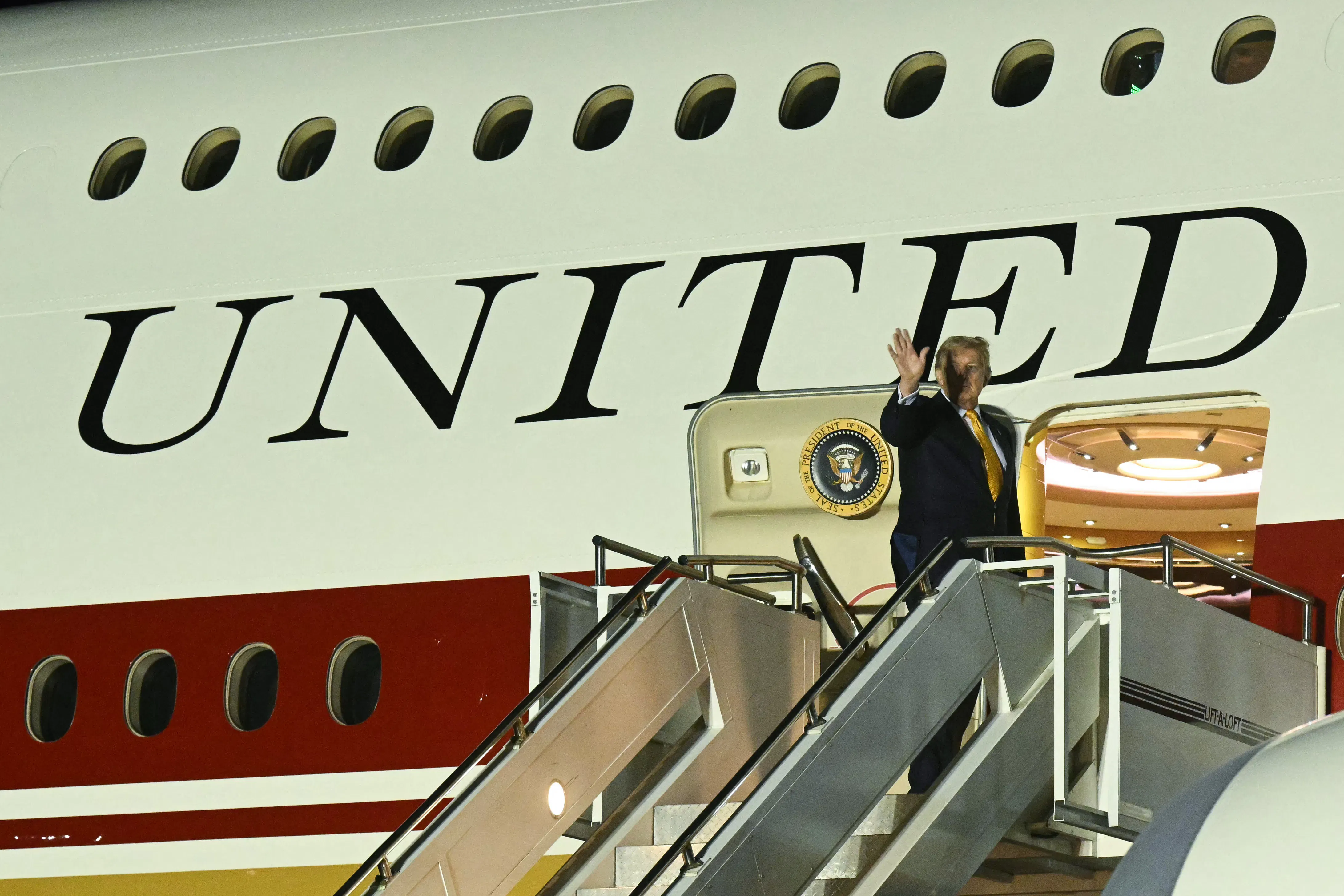 U.S. President Donald Trump waves while boarding the new Air Force One,