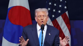 Donald Trump raises both hands while speaking at a podium during a summit in South Korea