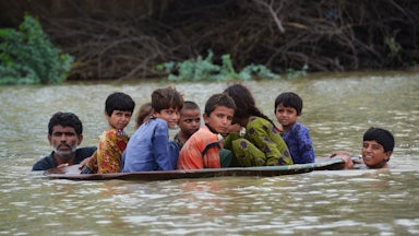 A man uses a satellite dish to move children across a flooded area after heavy monsoon rainfalls in Balochistan, Pakistan