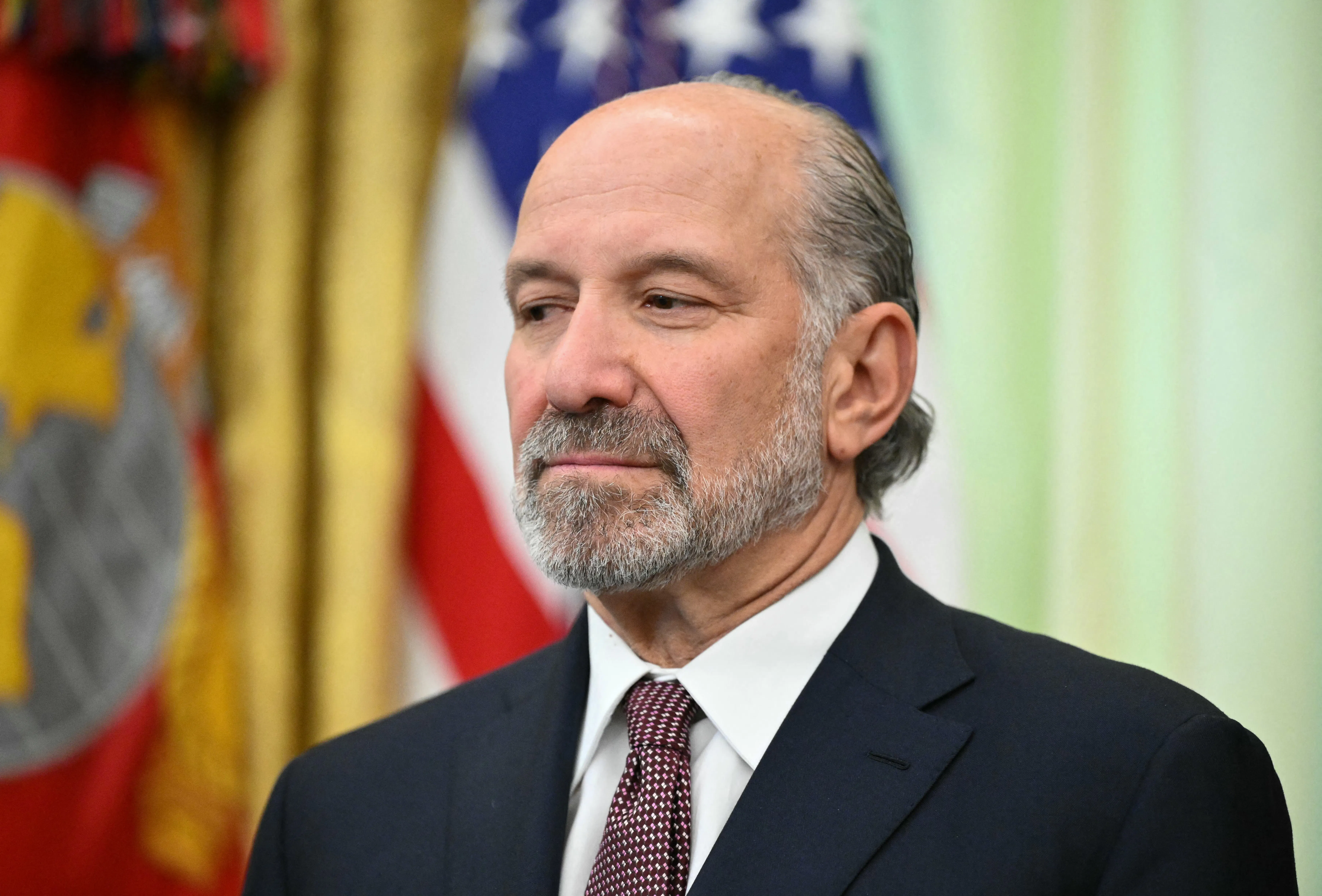 Commerce Secretary Howard Lutnick smiles slightly and stares off into space