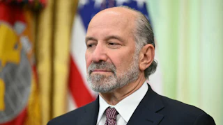 Commerce Secretary Howard Lutnick smiles slightly and stares off into space