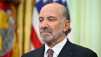 Commerce Secretary Howard Lutnick smiles slightly and stares off into space