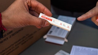 A hand holds an unused COVID-19 rapid antigen test.