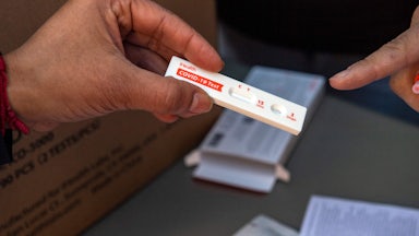 A hand holds an unused COVID-19 rapid antigen test.