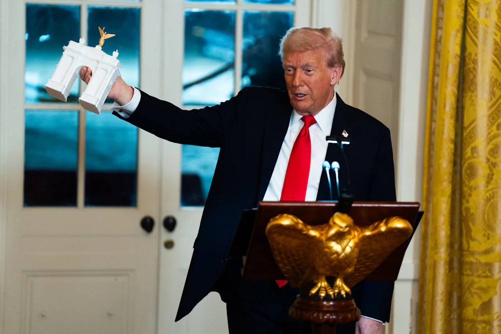 Trump holds up a model of his planned triumphal arch