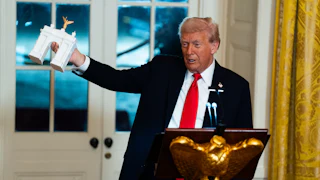 Trump holds up a model of his planned triumphal arch
