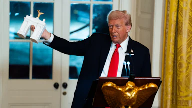 Trump holds up a model of his planned triumphal arch