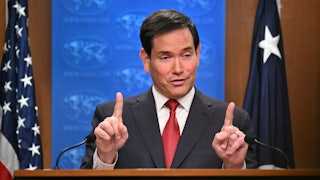 Secretary of State Marco Rubio raises both index fingers while speaking at a podium