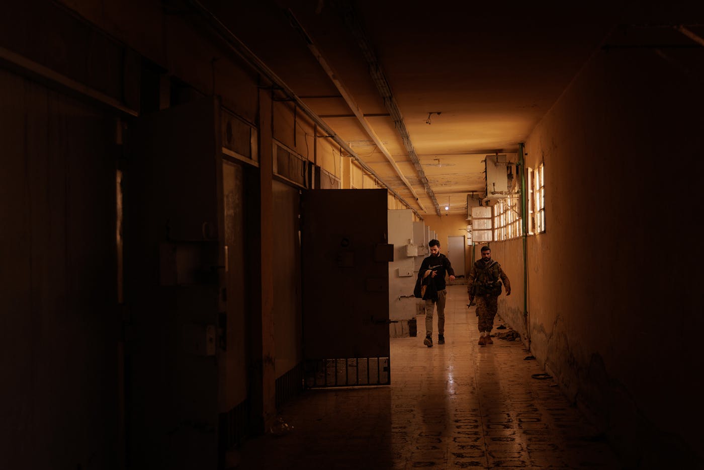 Members of the rebel forces who helped liberate the prison from the Assad regime walk down a cell corridor at Sednaya Prison. 