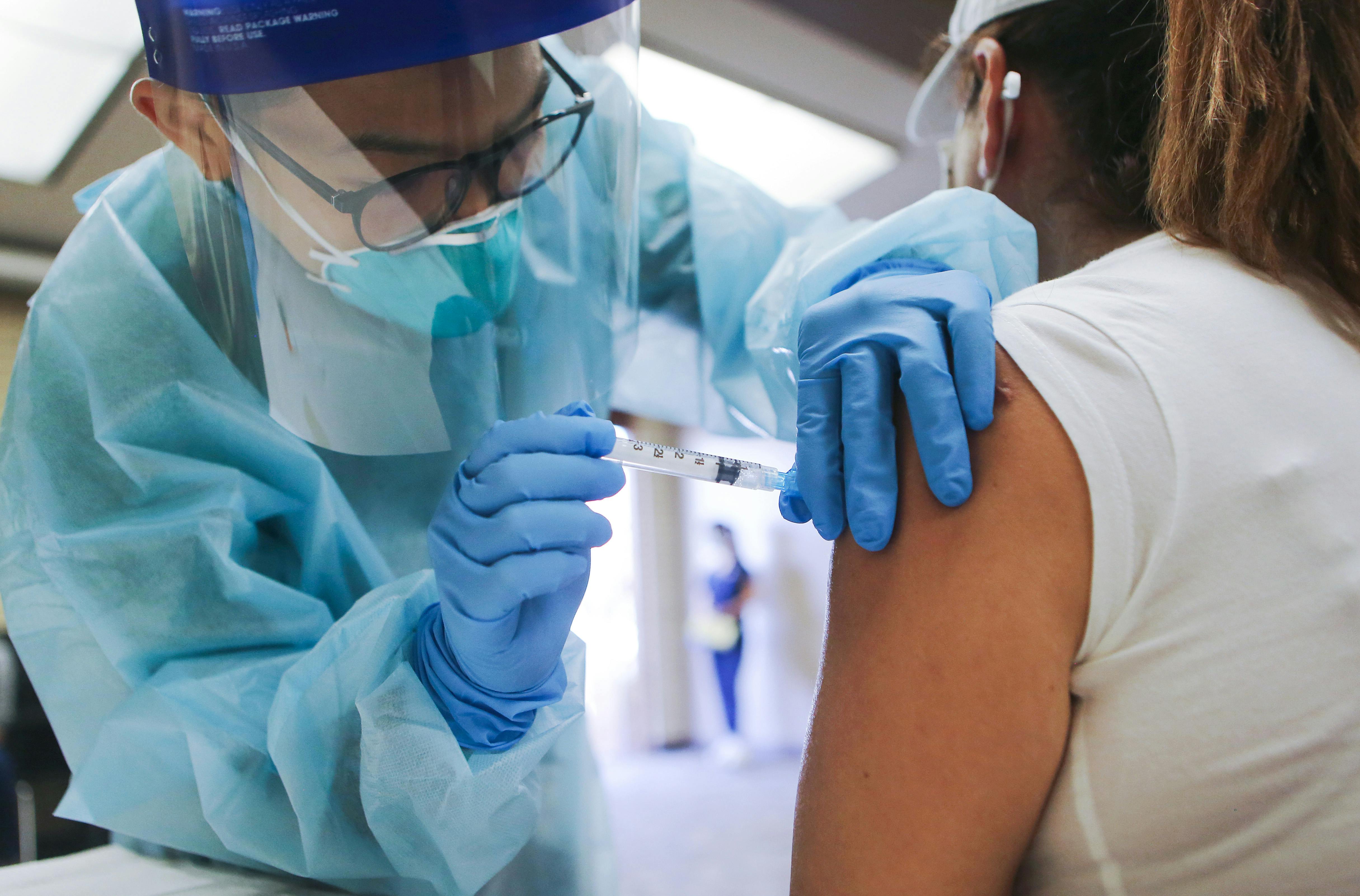 A nurse administers a flu shot at a free clinic, wearing protective gear against Covid-19.