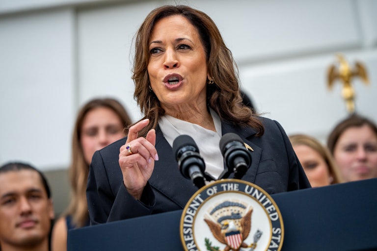 Kamala Harris speaks at a podium. Others stand behind her.