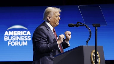 Donald Trump raises his fists and dances while standing at a podium on stage at the American Business Forum
